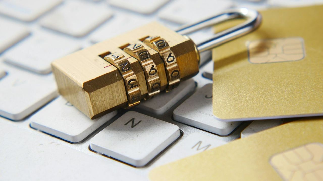Un cadenas à code posé sur un clavier à côté de cartes bancaires