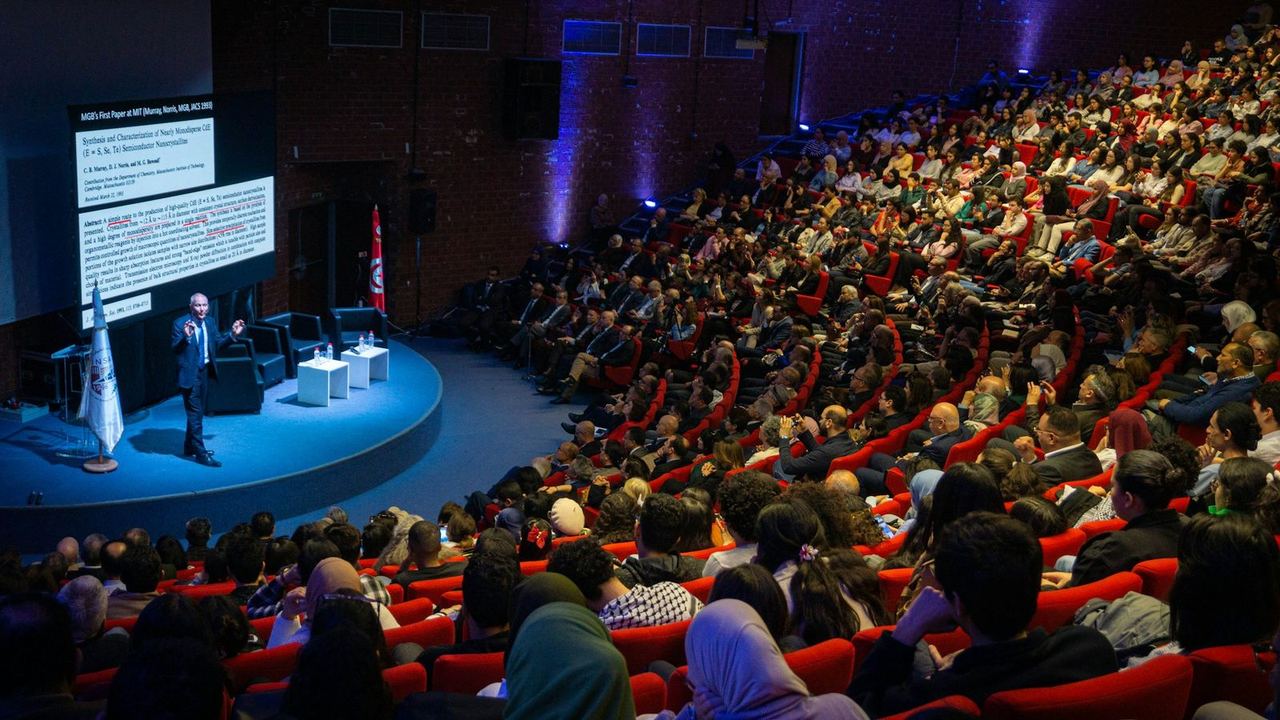 Un intervenant sur scène devant un large public dans un auditorium
